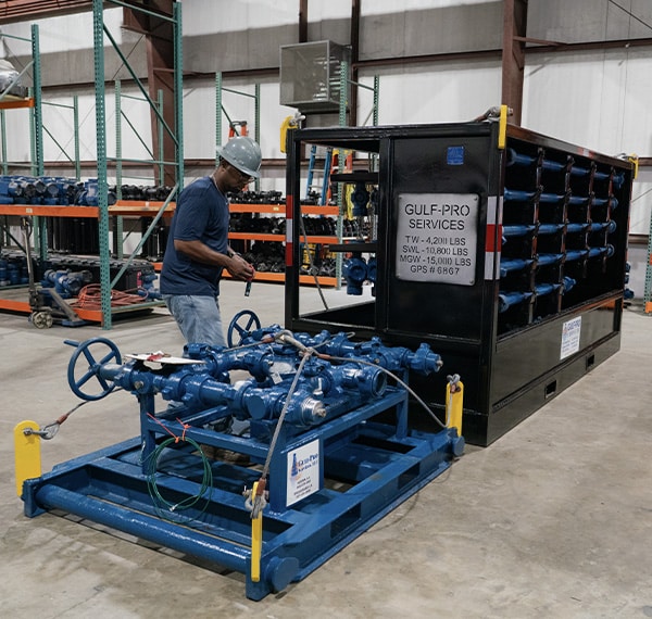 equipment-inspection Gulf-Pro technician inspecting high-pressure manifold system in warehouse